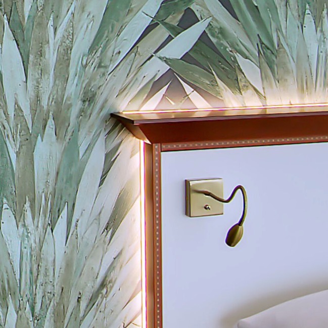 Headboard with reading lamp against palm-leaf wallpaper