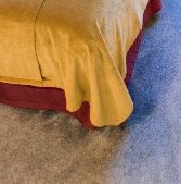 Mustard-coloured bedspread draped over the bed base