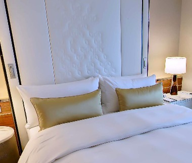 Bed with quilted headboard and olive-green cushions